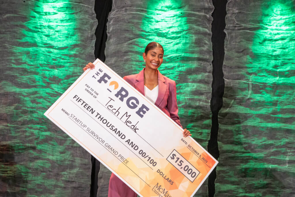 Grand prize winner, Shania Bhopa, posing on stage with cheque